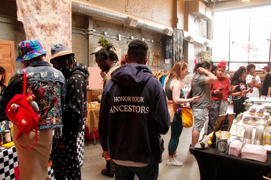 Guests gathered around the food tables at a Mindful Matter Market in a Brooklyn warehouse