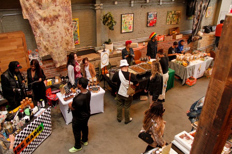 Visitors browsing wellness and food stalls beneath hanging artwork at a Mindful Matter Market