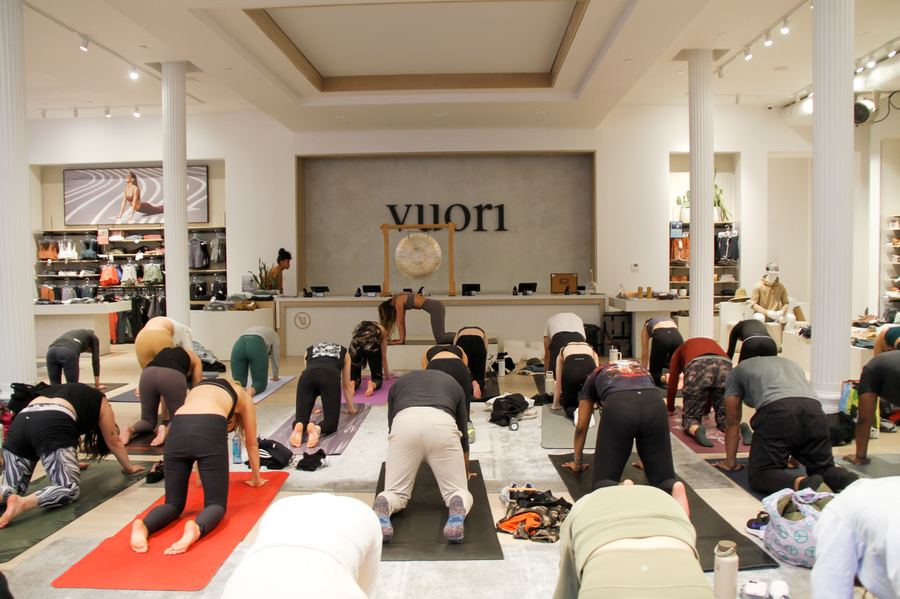 A group yoga class moving through downward dog at a Mindful Matter Market brand activation